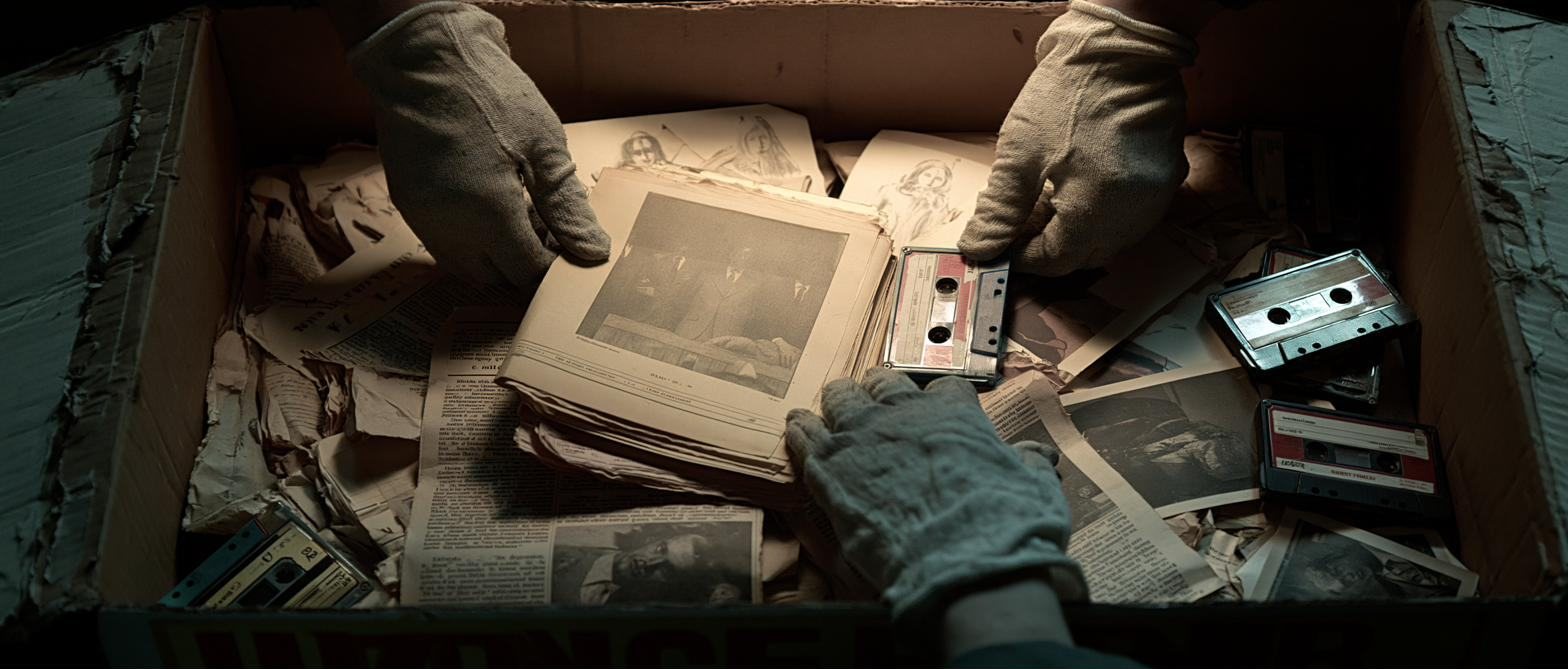 Gloved hands opening an archive box of photographs and tapes.