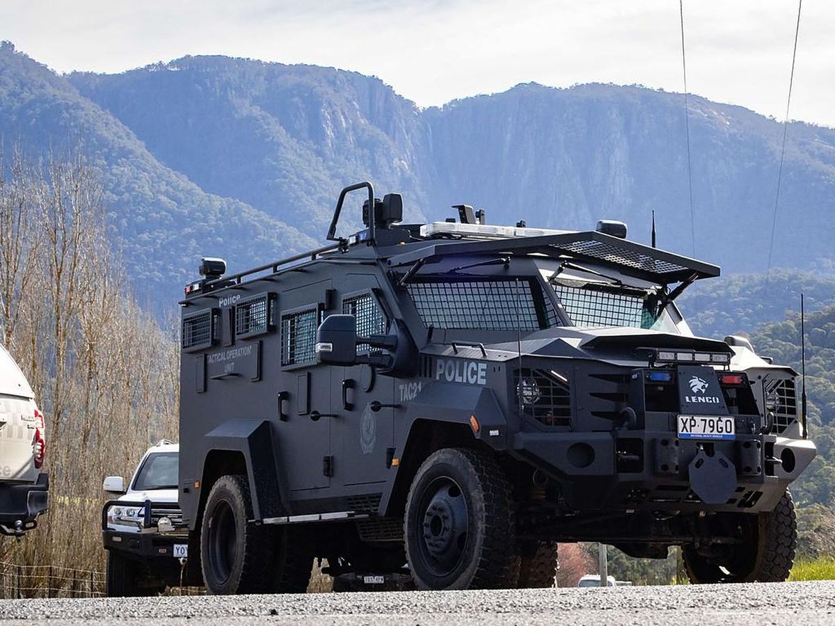 An armoured police vehicle on a country road beneath the granite walls of Mount Buffalo.