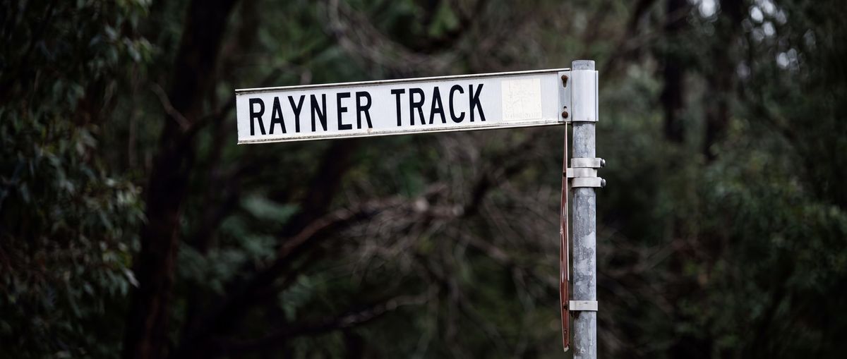 The Rayner Track road sign against dark bush.