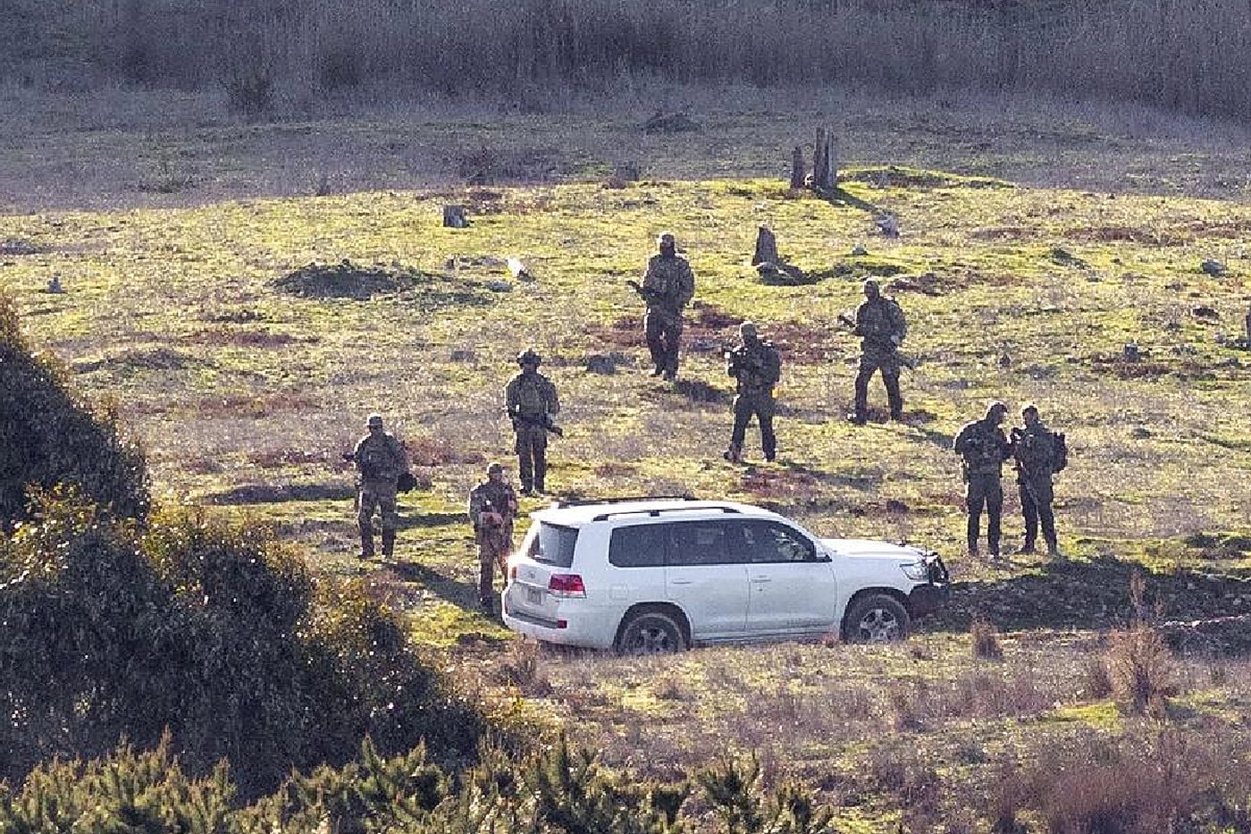 Camouflaged tactical hunters sweep a paddock during the search.