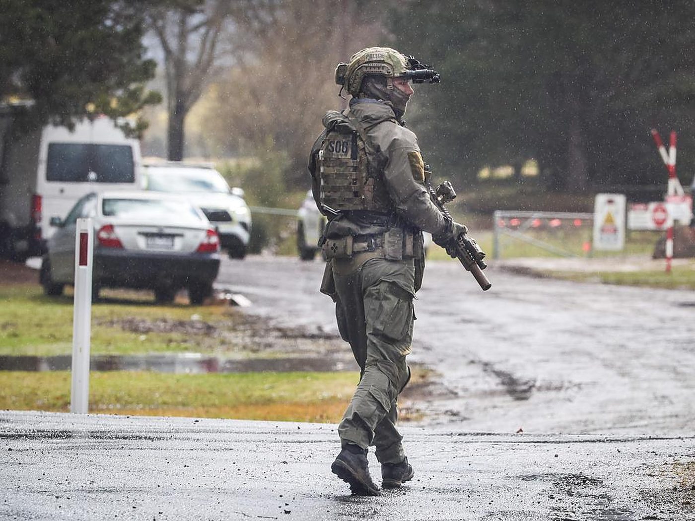 A tactical officer walking through rain on a closed country road.