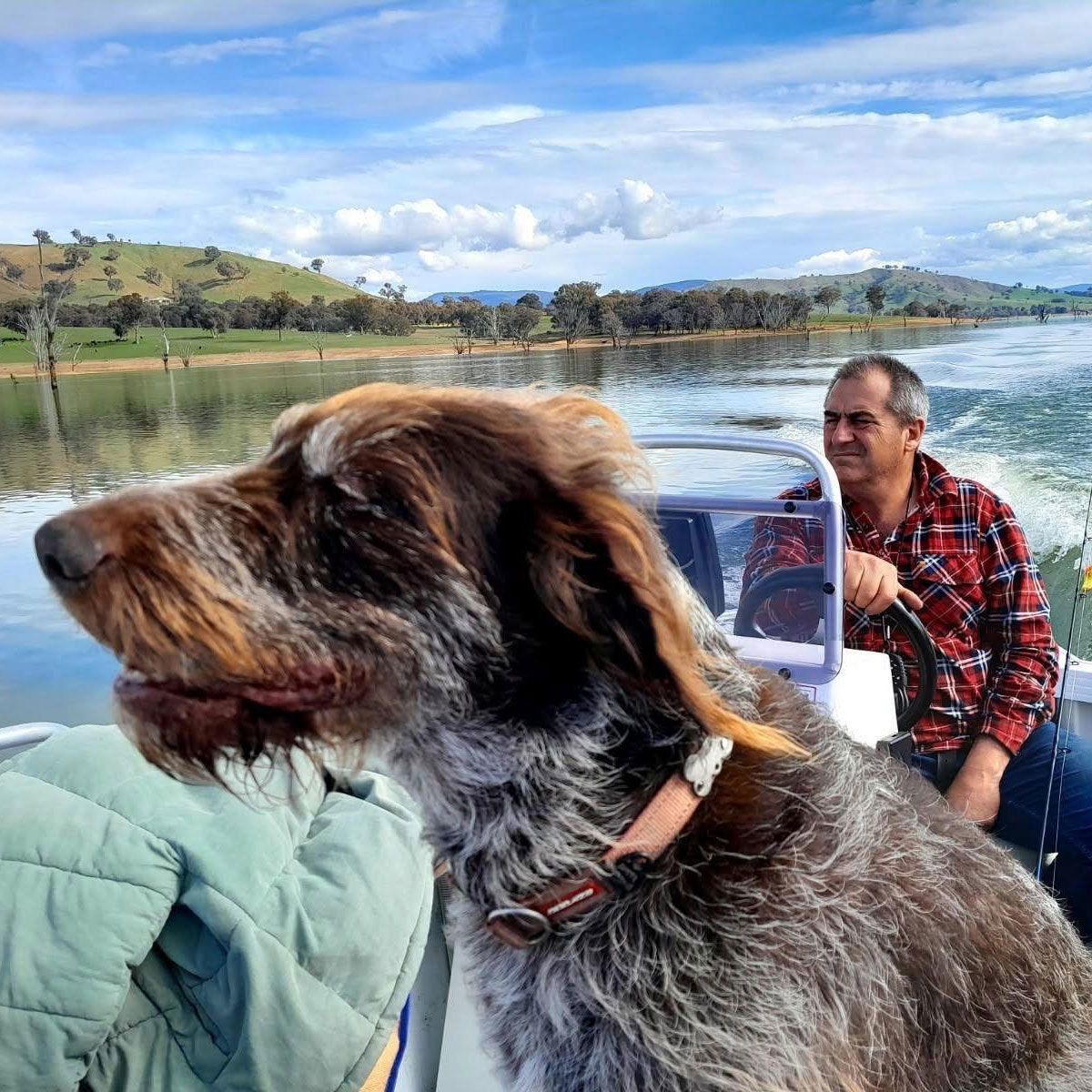Neal Thompson on the water in his boat, his dog beside him.