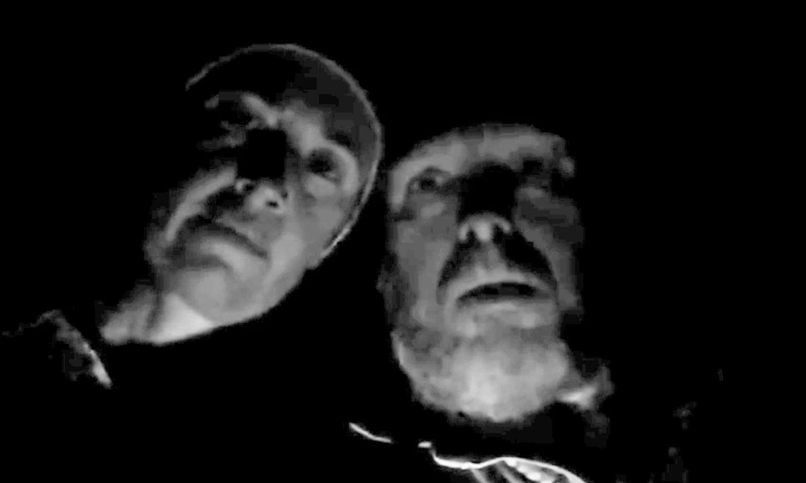 A grainy black and white frame of Gareth and Stacey Train staring up into their own camera at night.